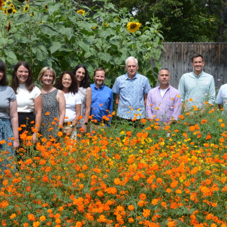 A group of people from Applewood Seed and the City of Arvada pose for a photo surrounded by flowers.