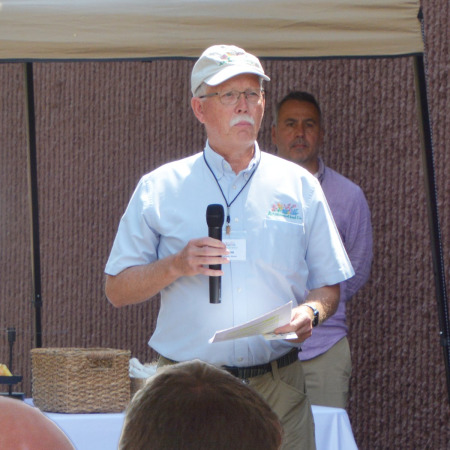 Applewood Seed CEO Norm Poppe stands with a microphone.